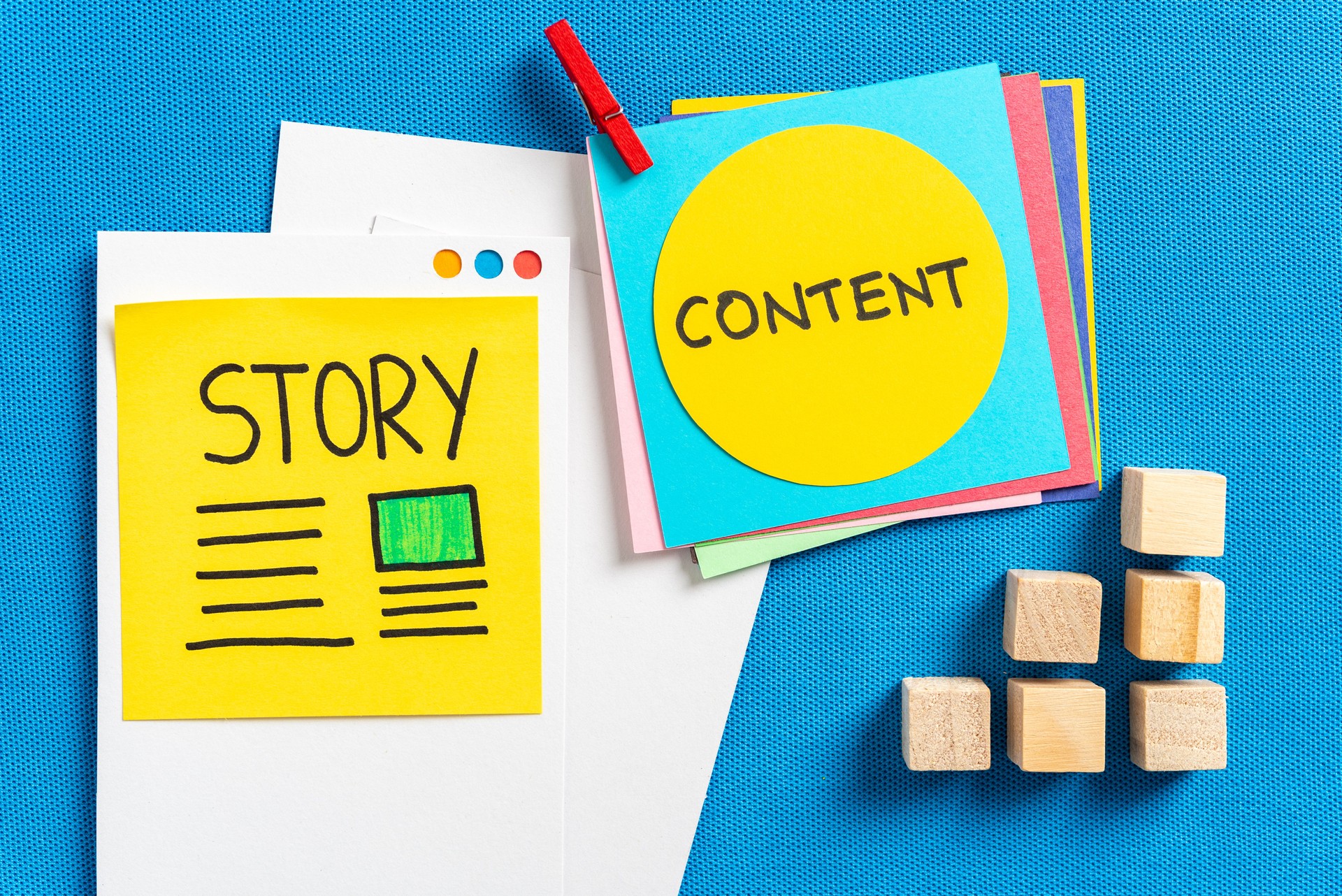 Social media content sharing, storytelling and digital marketing concept made with cut colorful papers and the illustrated words "story" and "content" and wooden block toys on blue texture background.